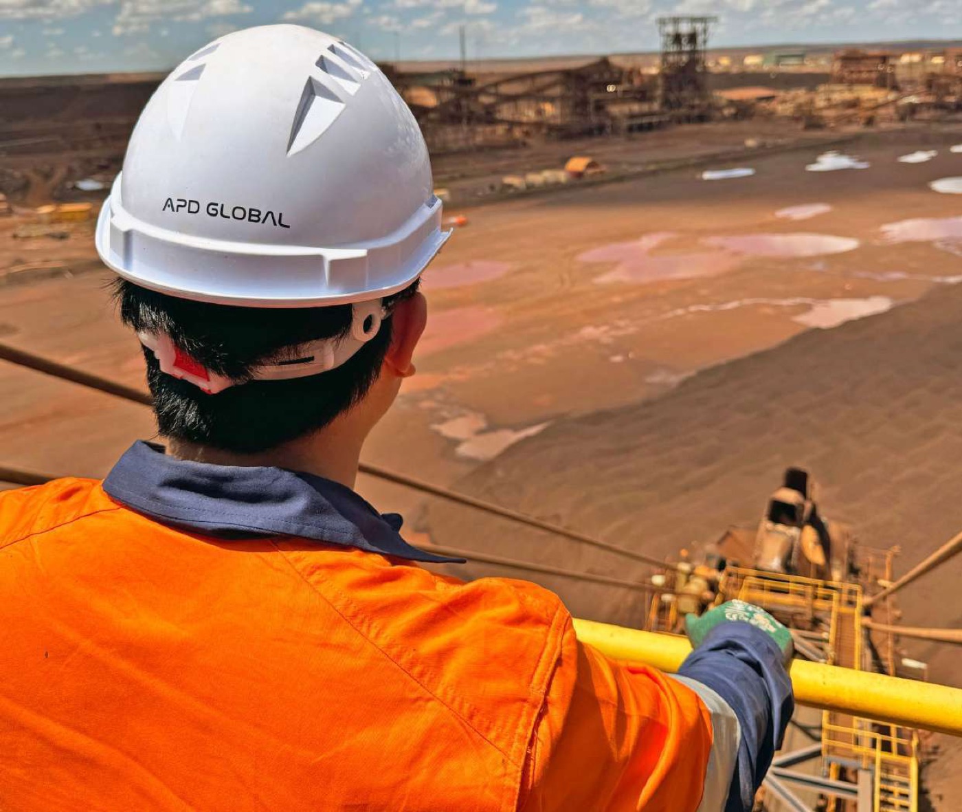 APD engineer in branded hard hat overlooking a mining and processing site